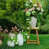 Floral arrangements in vases on stool and ground